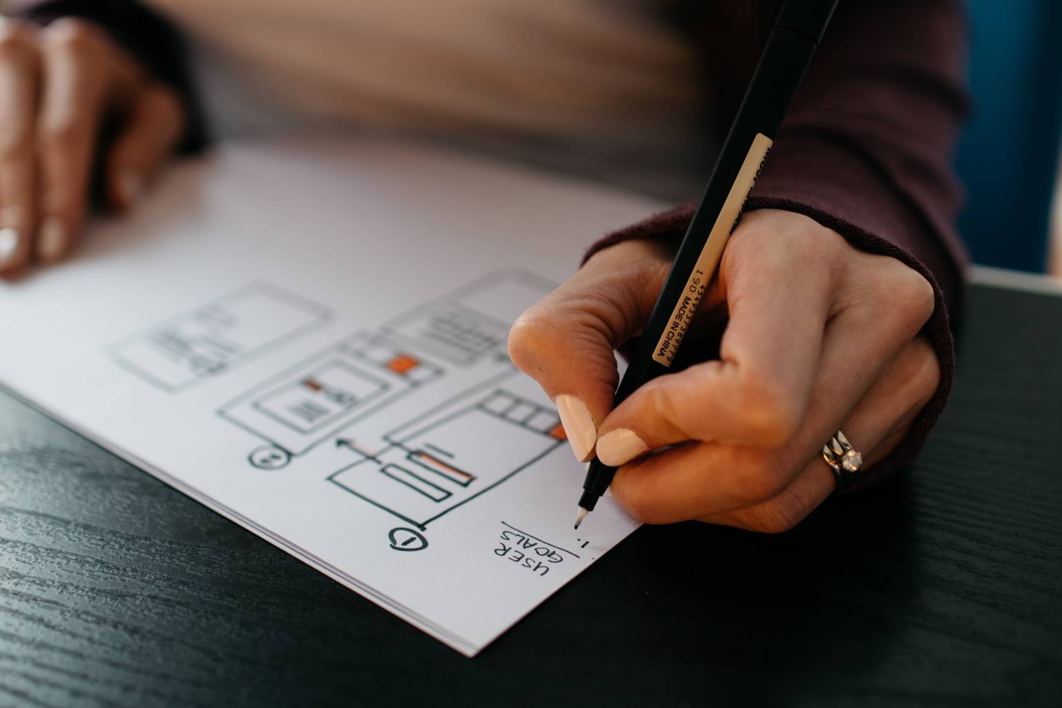 Image of a woman writing on a piece of paper with a pen image on Nemphos Braue's website