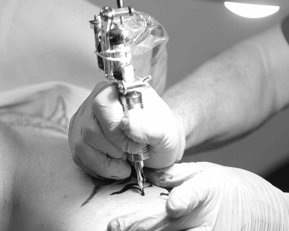 Image of a person giving another person a tattoo